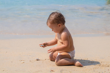 快乐的孩子在夏天在蓝色的海面上玩耍。婴儿在海滩上爬行, 玩玩具