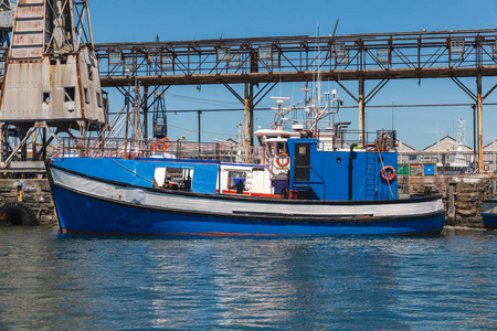 站在码头旁的蓝色小拖网渔船