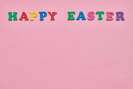 粉红色复活节背景。 五颜六色的字母形成单词快乐复活节在粉红色的背景。 复制您的文本空间。 复活节庆祝概念的平面布局。