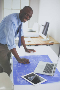 非洲裔美国建筑师在办公室使用计算机和蓝图