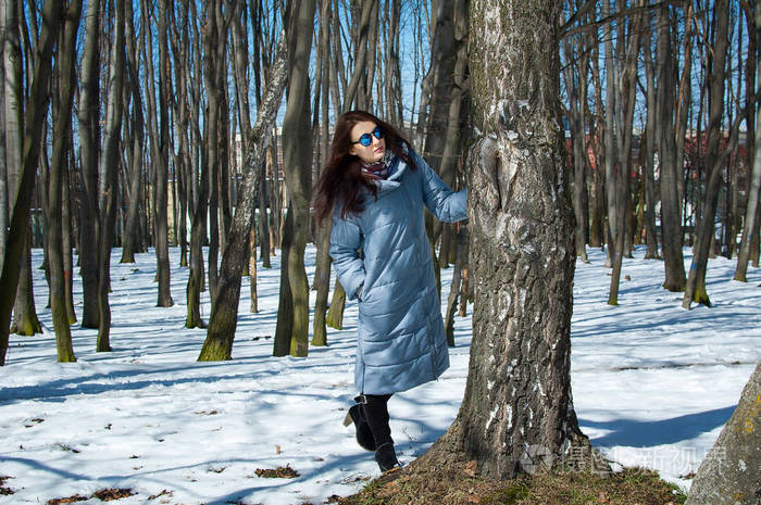 在早春期间, 公园里户外赤脚站在户外的户外, 戴着太阳镜和蓝色冬衣的
