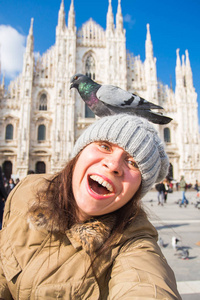 旅行, 假期和寒假概念快乐的年轻女子在大教堂米兰大教堂前与有趣的鸽子自拍照片