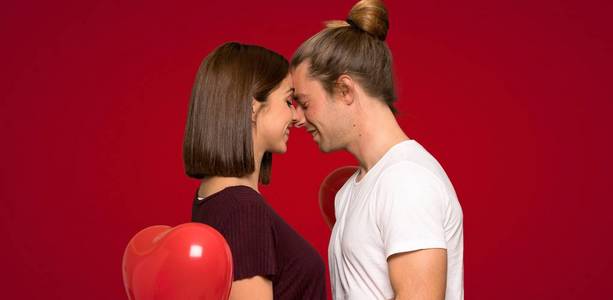情人节的一对夫妇，在红色背景下愉快地表达着快乐的表情