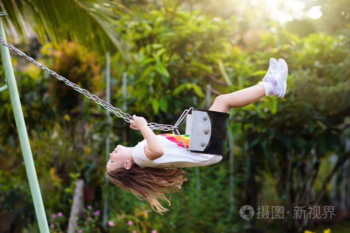 孩子在公园里阳光明媚的夏日在操场上摇摆. 孩子们荡秋千.