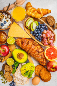 白色背景下健康平衡早餐。 梅斯利果汁牛角面包奶酪饼干和水果的顶部视图。