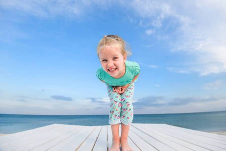 夏天海滩上的小漂亮女孩看着镜头特写。 一个快乐微笑的女孩的肖像