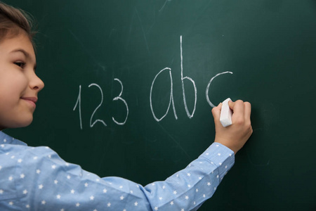 小孩在黑板上写字母和数字