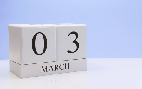 三月三日 月03日每日日历在白色桌子上，反射浅蓝色背景。 春天的时间，空的文字空间
