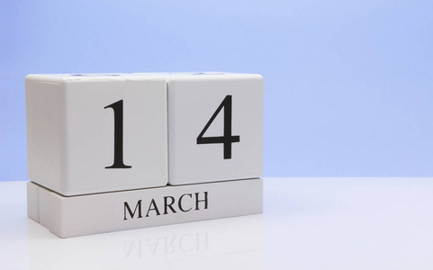 三月十四日 月14日每日日历在白色桌子上，反射浅蓝色背景。 春天的时间，空的文字空间