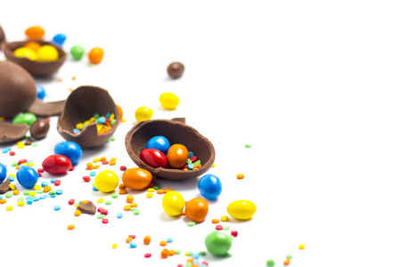 碎的和整个巧克力复活节彩蛋，白色背景上的五彩糖果。庆祝复活节的概念，复活节装饰品，寻找复活节兔子的糖果。平躺，俯视。复制空间