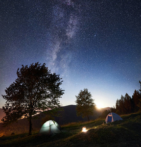 两个发光的帐篷和篝火在惊人的夜空下充满星星和银河