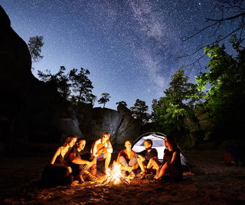 夜晚，朋友们一起坐在篝火旁的旅客们