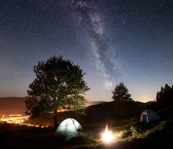 两个发光的帐篷和篝火在惊人的夜空下充满星星和银河