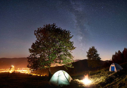 两个发光的帐篷和篝火在惊人的夜空下充满星星和银河