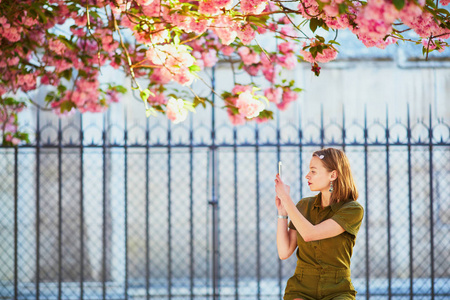 美丽的法国女人在樱花季的春日漫步在巴黎