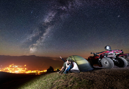 青年男女坐在山顶的旅游帐篷里，开着四辆摩托车