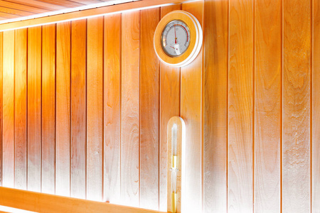 传统木制桑拿浴室墙上的圆形温度计和沙漏