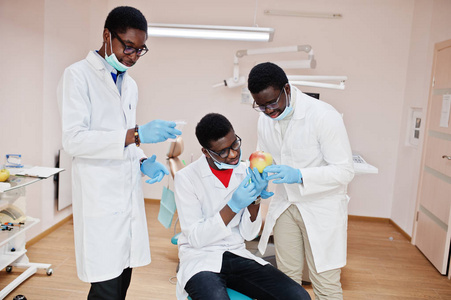 三名非裔美国男医生同事在牙科诊所用苹果。