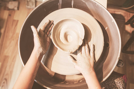 年轻的陶工在车间的陶轮上用粘土制作陶瓷花瓶
