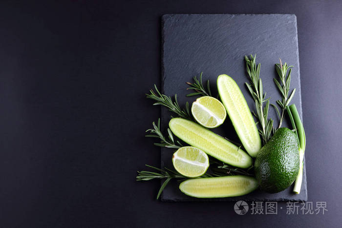 黑色背景下的绿色水果,蔬菜和迷迭香 天然绿色产品的创意形象.