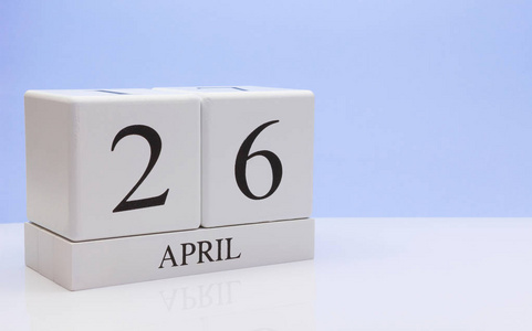 四月二十六日。 月26日每日日历在白色桌子上，反射浅蓝色背景。 春天的时间，空的文字空间