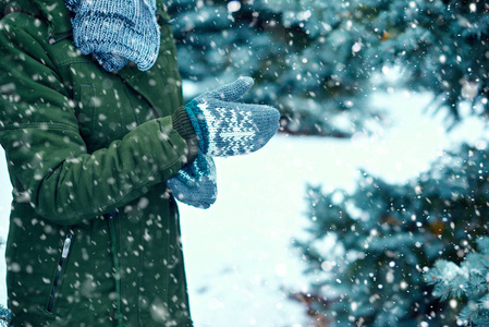 女人穿着手套在冬天的森林绿杉树和雪。