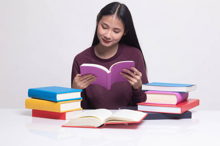 一位年轻的亚洲妇女读一本书，书上放着白色背景的书