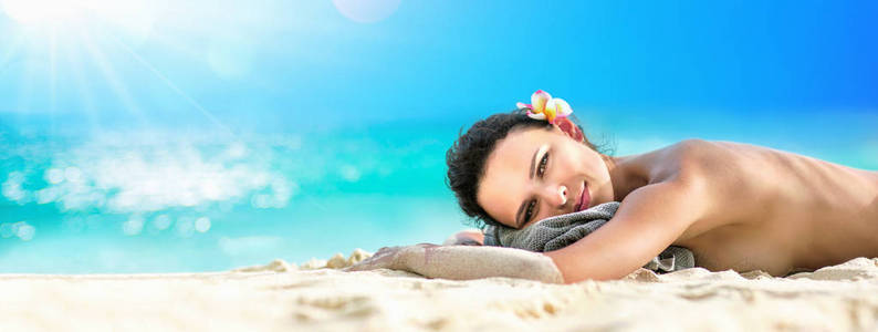 美丽的女孩躺在阳光下晒黑在热带海滩