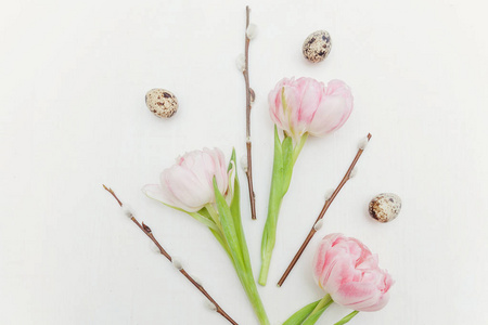 春天的贺卡。 复活节彩蛋，棉柳枝和粉红色新鲜郁金香花束在乡村白色的木制背景上。 复活节的概念。 平躺顶部视图复制空间。 春花郁金