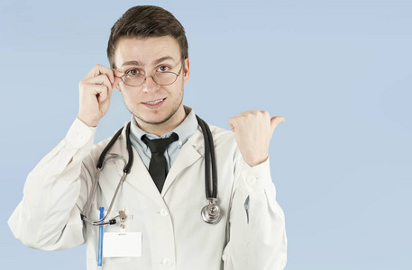 年轻的男性医生医务工作者在蓝色背景上孤立的空地上展示。 概念是空着的