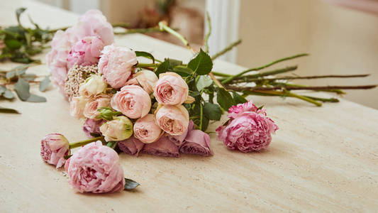 鲜花店的桌子上放着玫瑰和牡丹花束