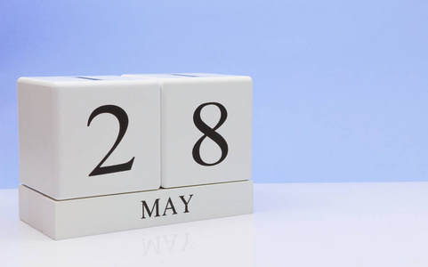 五月二十八日。 月28日每日日历在白色桌子上，反射浅蓝色背景。 春天的时间，空的文字空间