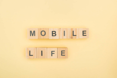 用黄色背景的木立方体制作的Mobil生活字体的俯视图