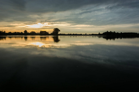 日落时的乌云笼罩着平静的湖景傍晚