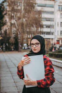 年轻的穆斯林女孩在笔记本电脑上打字