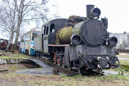 狭窄轨距铁路的旧生锈机车。 旧蒸汽机车的停泊地点。 秋天的季节。