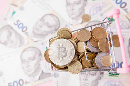 比特币和硬币在购物车上的hryvnia背景。