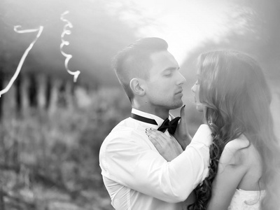 年轻的新婚夫妇在森林里用彩带装饰着结婚礼服在户外接吻