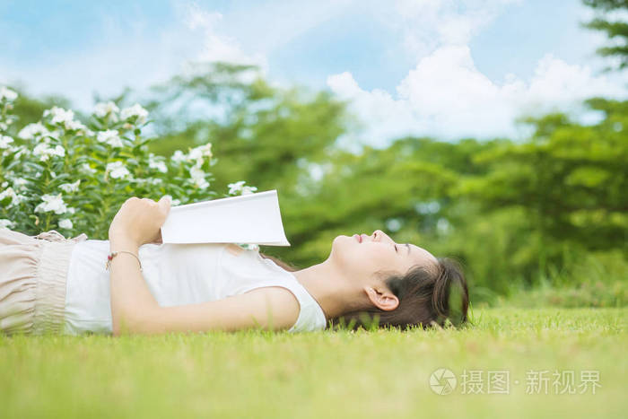 一个亚洲女人在下午看了一本书后躺在草地上