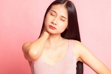 年轻的亚洲女人在粉红色背景下脖子疼