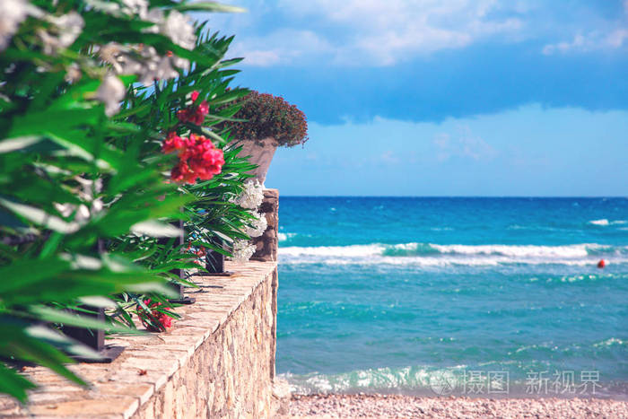 蓝色的大海和白色的石墙,有鲜花,在希腊岛上的景色,旅游目的地