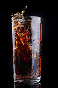 用冷饮把冰倒进杯子里。 把饮料溅到酒吧里。 黑暗的背景。