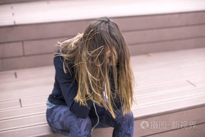 愁眉苦脸悲伤沮丧的年轻女子坐在外面