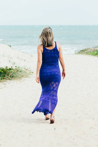 穿着蓝色连衣裙在海滩上放松的年轻女子的肖像。