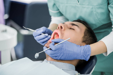 戴乳胶手套的女性牙科医生用张开嘴检查病人