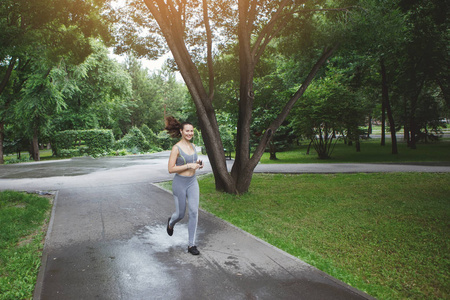 年轻女子沿着绿色公园的小径慢跑