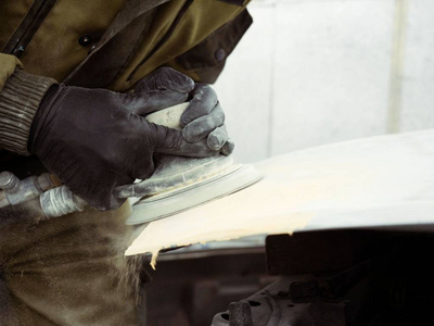 s hands in black gloves polish the hood of the car with a pneuma