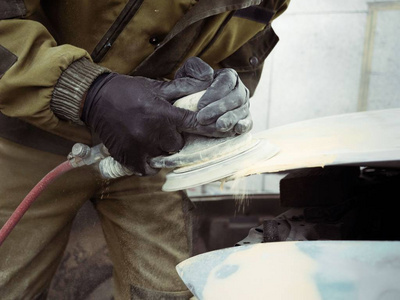 s hands in black gloves polish the hood of the car with a pneuma