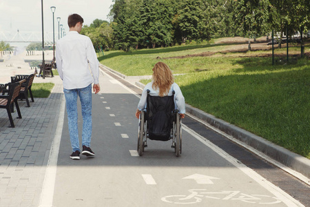 坐轮椅的女人和男朋友在城市夏季公园散步