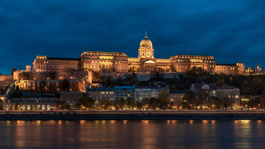 布达城堡俯瞰布达佩斯多瑙河。 城堡在夜间被点亮，灯光反射在河上
